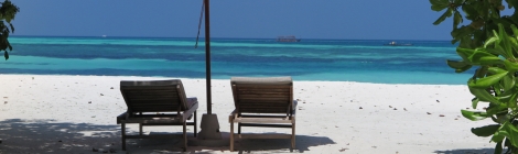 white beach with two lounge chairs and an umbrella